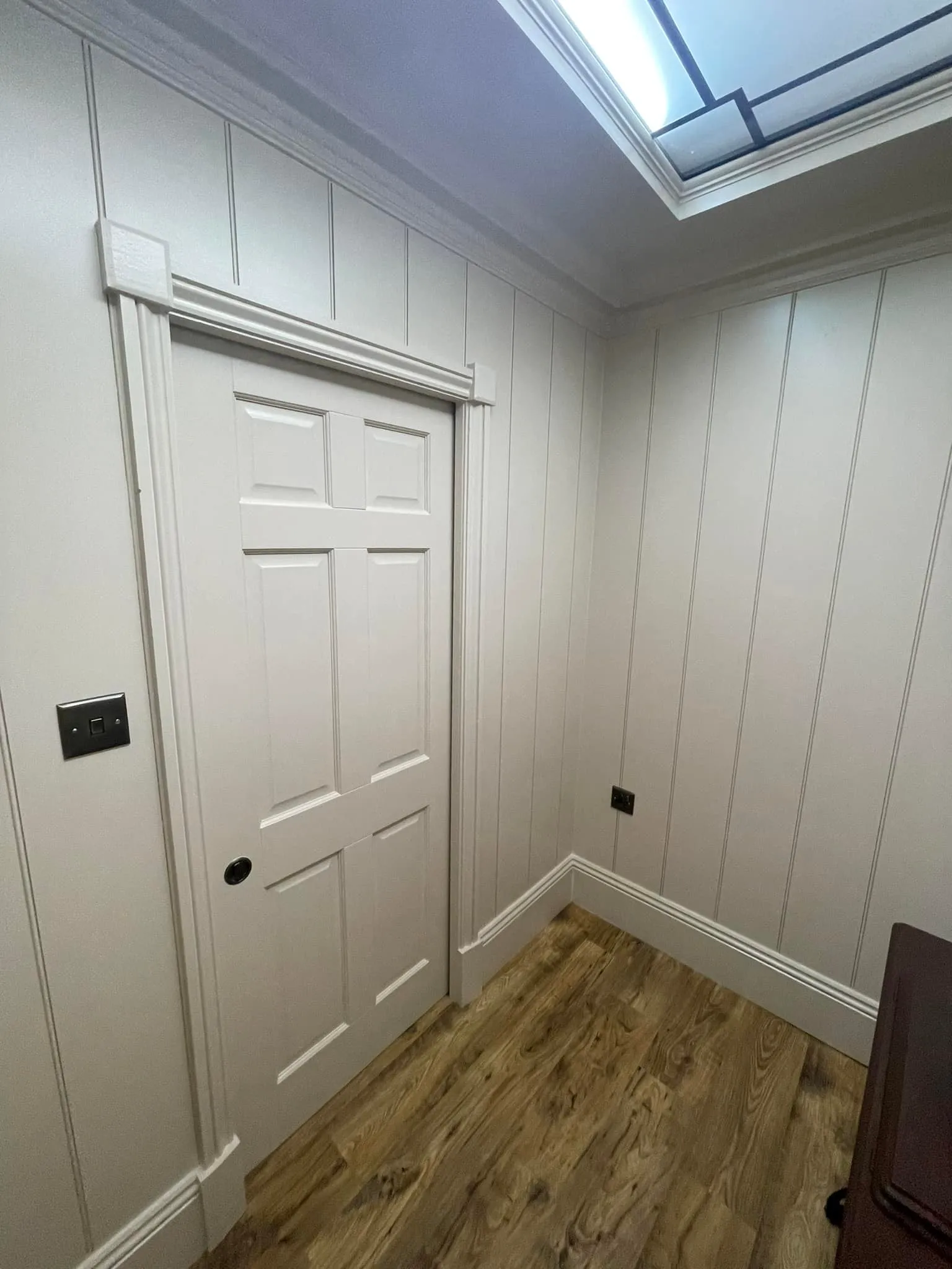 A white room with a skylight and wooden floors.