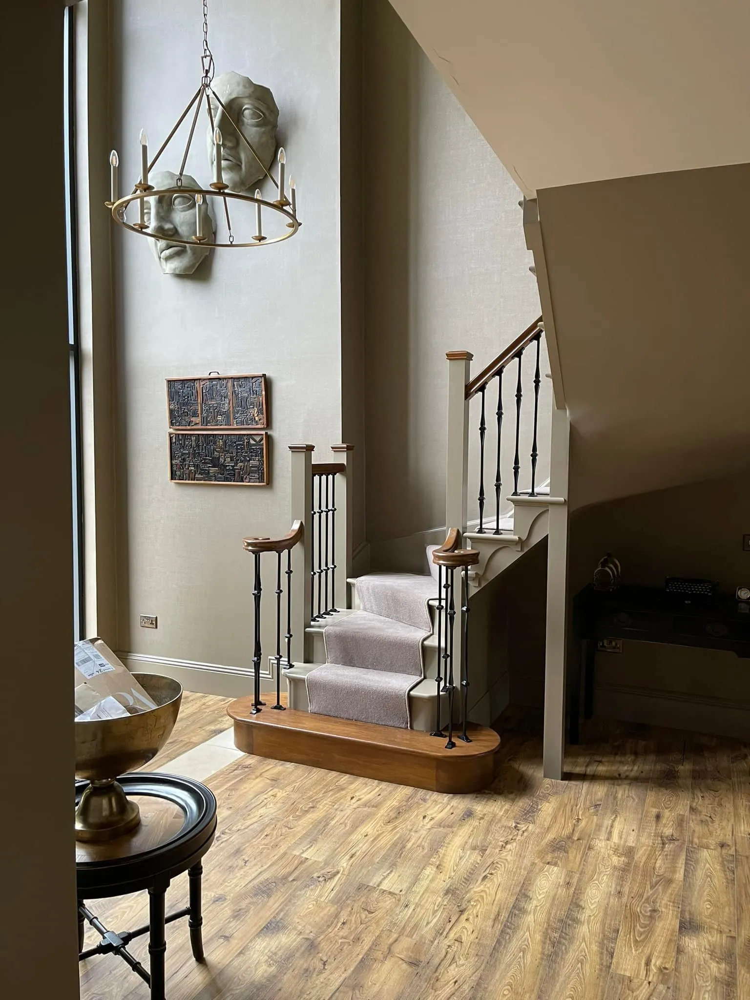 A living room with a staircase and a clock on the wall.